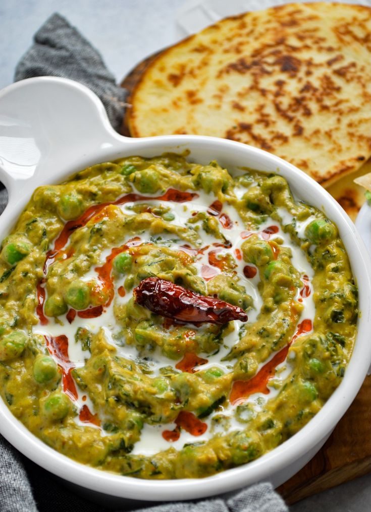 Creamy Methi Matar Malini curry garnished with fresh cream and chili oil in a white serving dish.